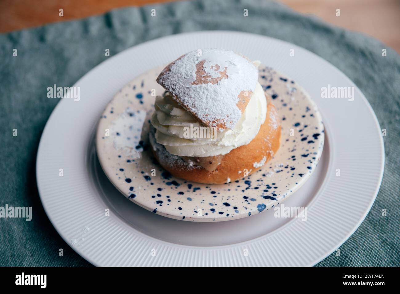 Typical Swedish semla with sweet cream on te blue textile. Stock Photo