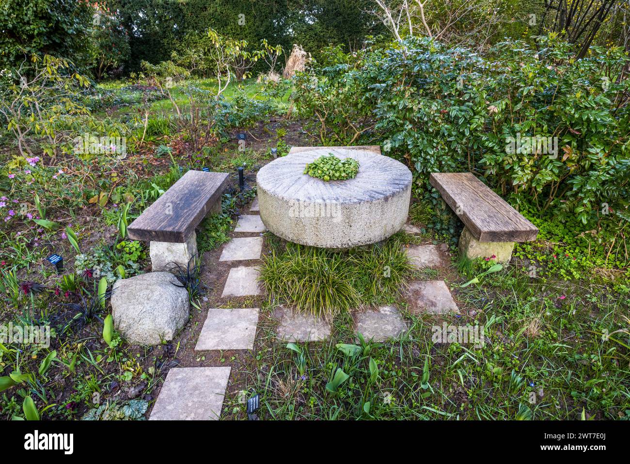 Millstone as a table with benches in the Karl Foerster Garden. Am Raubfang, Potsdam, Brandenburg, Brandenburg, Germany Stock Photo