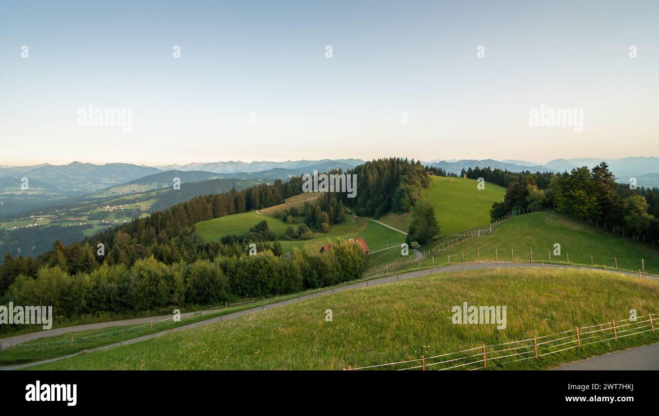 View from the top of Pfänder mountain at sunset - view at green alpine meadows, Bregenz Forest and range of Vorarlberg alpins in the background. Stock Photo