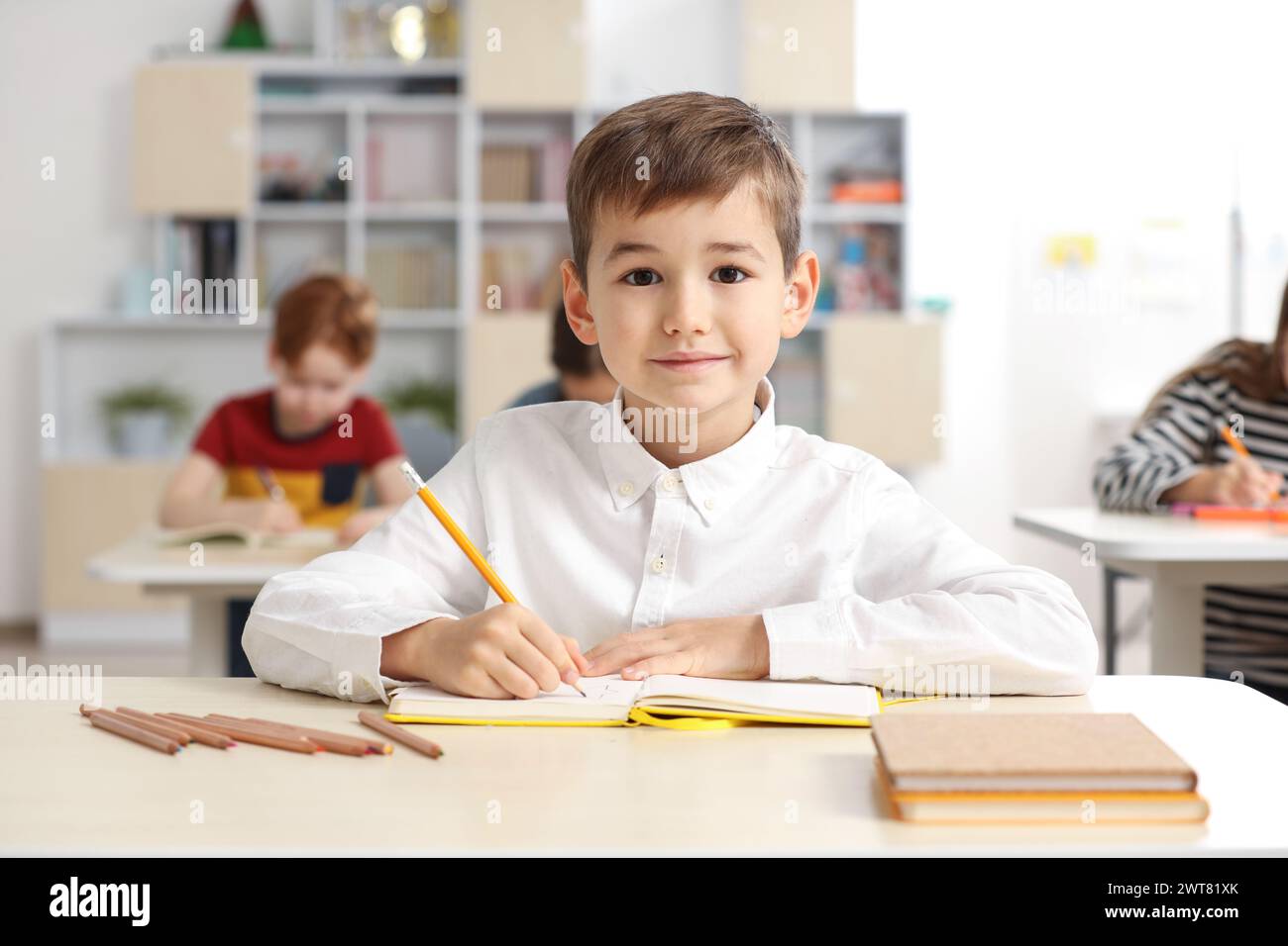 Portrait of cute little boy studying in classroom at school Stock Photo ...