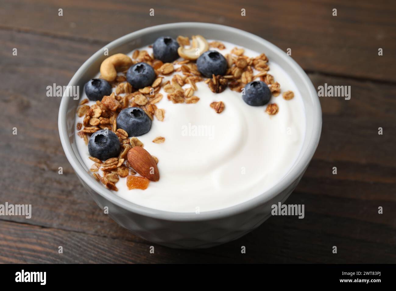 Bowl with yogurt, blueberries and granola on wooden table, closeup Stock Photo