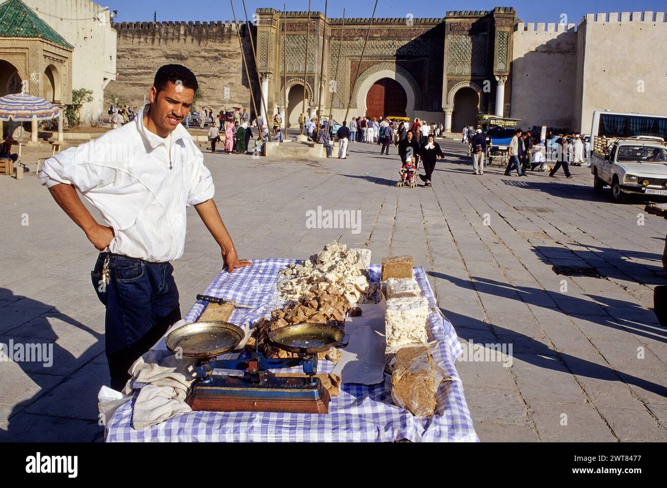Meknes, Morocco.  Place Hedime Candy Vendor.  Bab Mansour in Background, built 1672-1732, entrance to the imperial quarter. Stock Photo