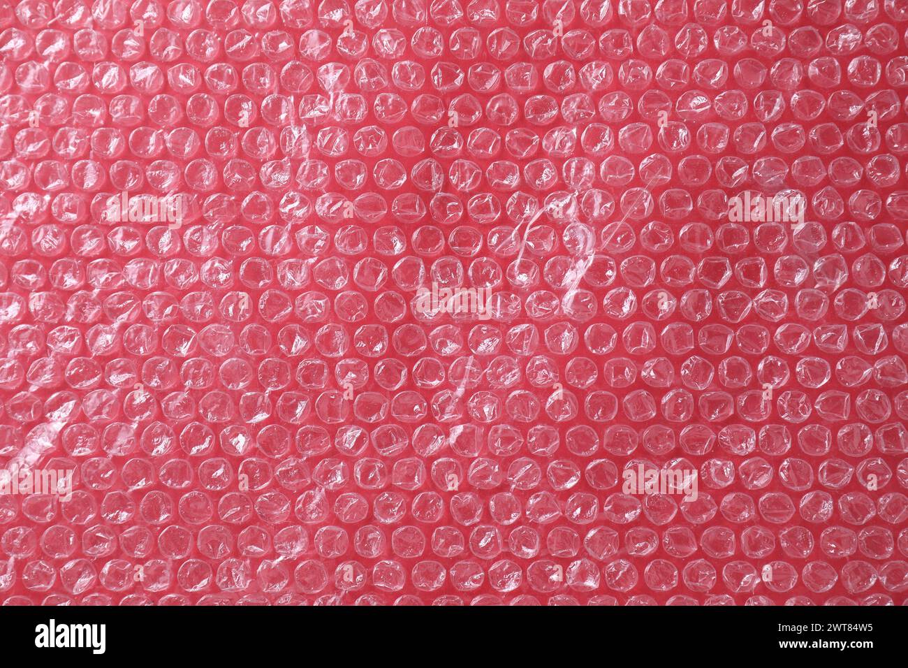 Transparent bubble wrap on red background, top view Stock Photo