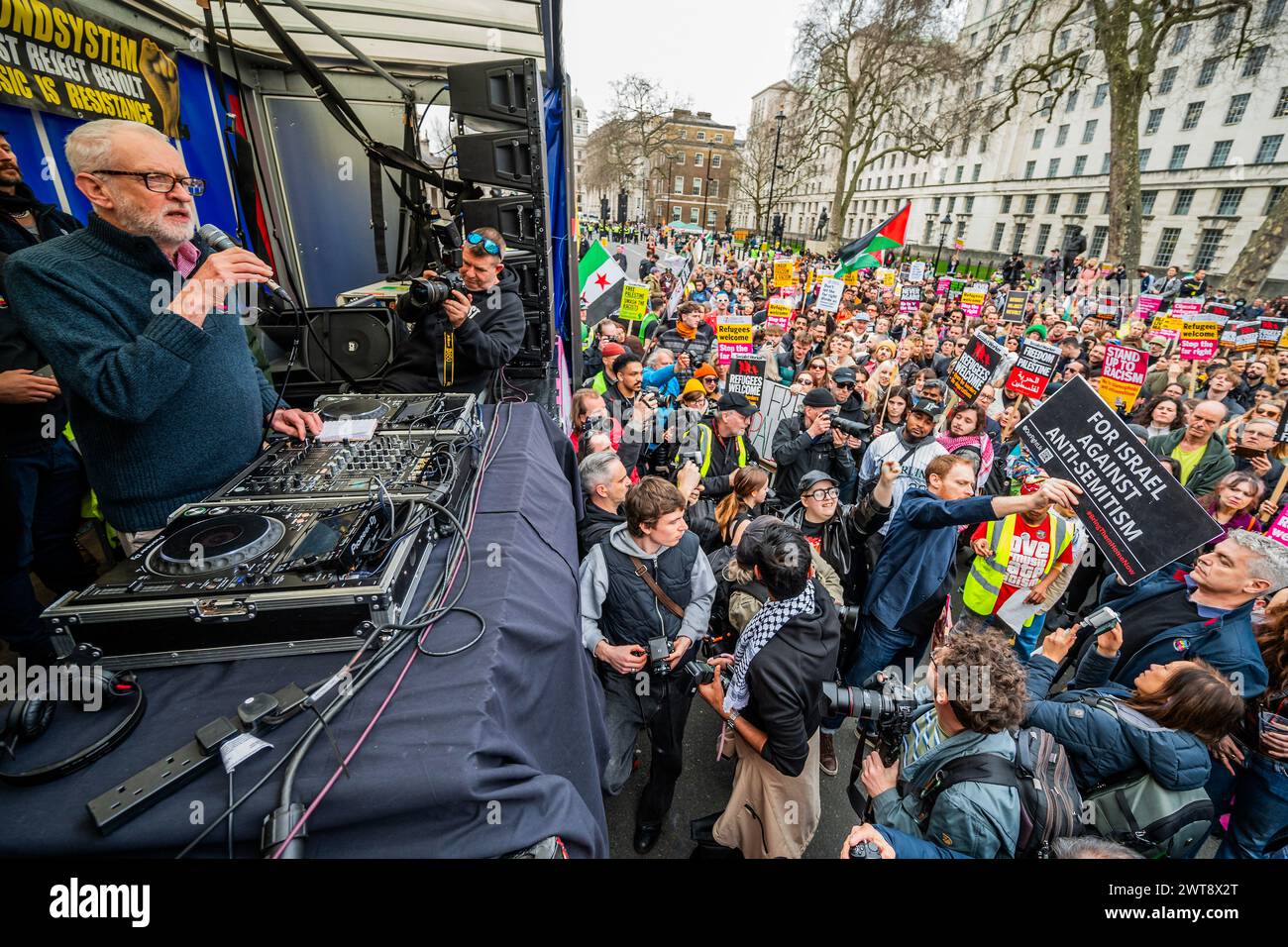 London, UK. 16th Mar, 2024. Jeremy Corbyn MP speaks as a lone pro Israel protester infiltrates the front of the crowd (his placard say bring them home and against anti-semitism) - House against hate dance music ravve outside downing Street. A Stop Racism, Stop the Hate demonstration in London. Credit: Guy Bell/Alamy Live News Stock Photo