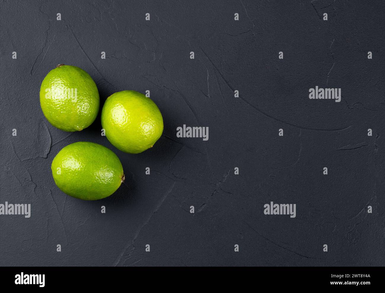Three lime fruits on an empty dark background, copy space Stock Photo