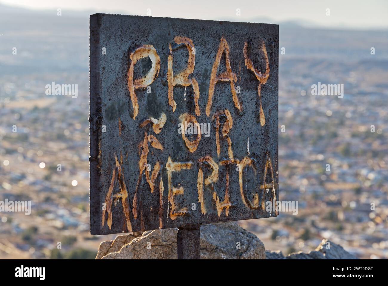 pray for America metal graffiti sign on top of a desert peak Stock Photo