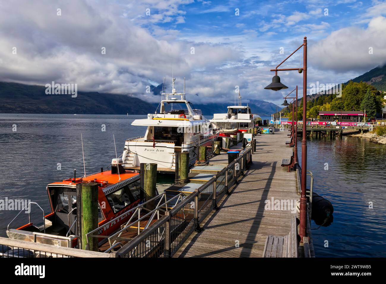 Queenstown, New Zealand - 24 Dec 2022: Main Queenstown city whaft with docked ships of adventure and experience services on Lake Wakatipu. Stock Photo