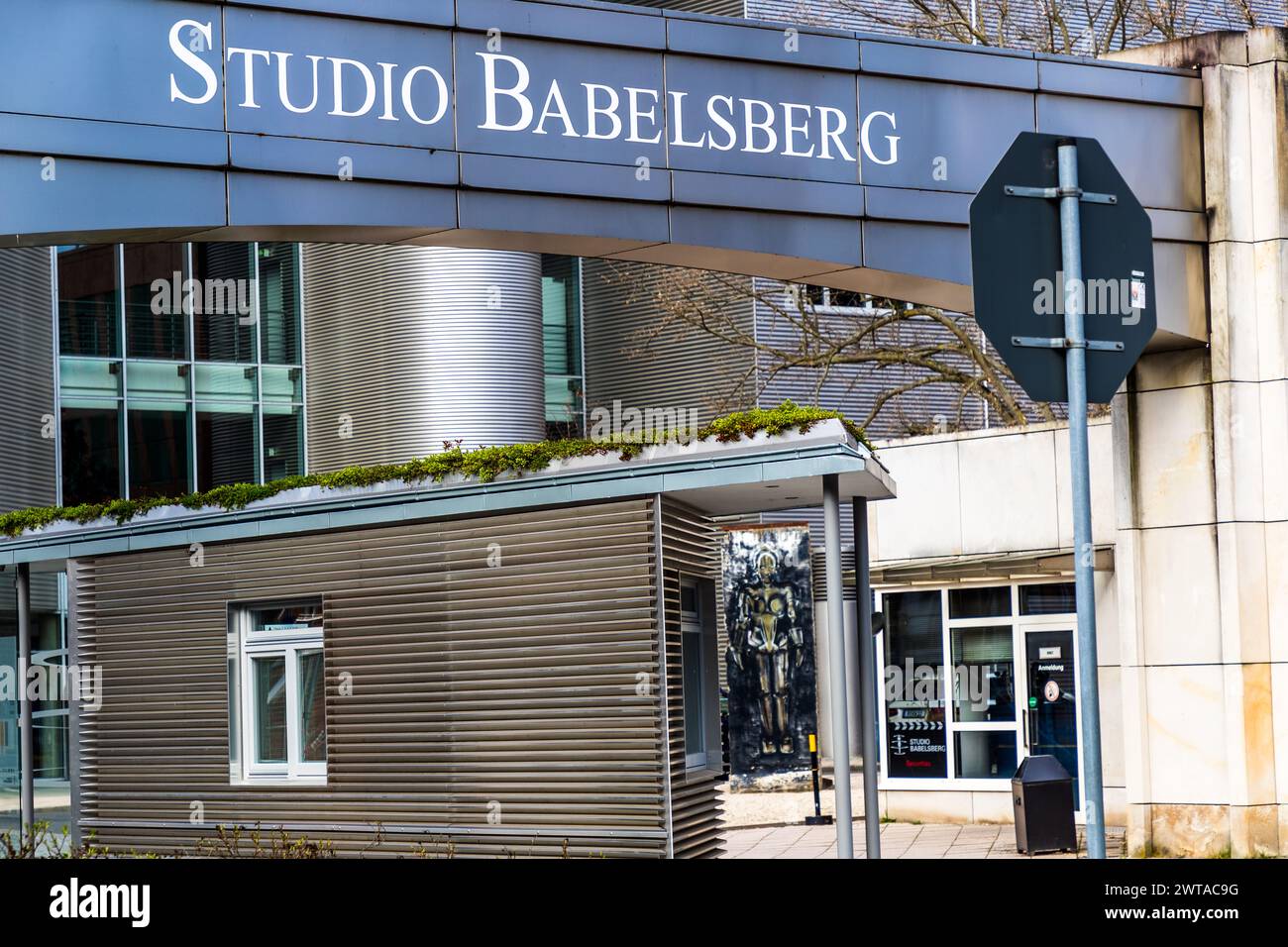Main entrance to Studio Babelsberg. In the background, a section of the Berlin Wall with the machine man Maria from the monumental Silent Movie Metropolis from 1927. Entrance and driveway to the Studio Babelsberg production site, August-Bebel-Straße, Potsdam, Brandenburg, Brandenburg, Germany Stock Photo