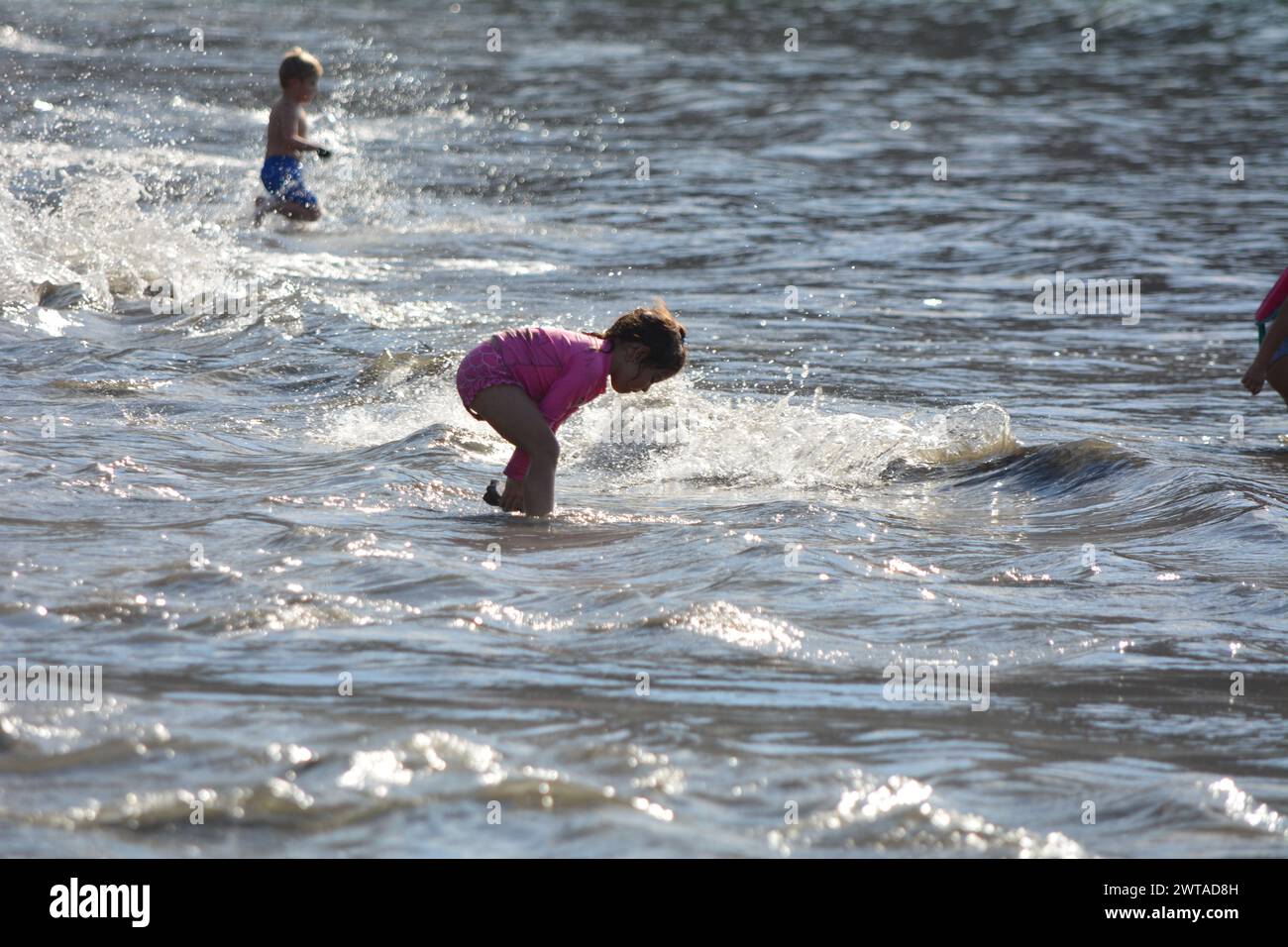 Children enjoying playing in ocean at Playa Hermosa, Costa Rica Stock Photo