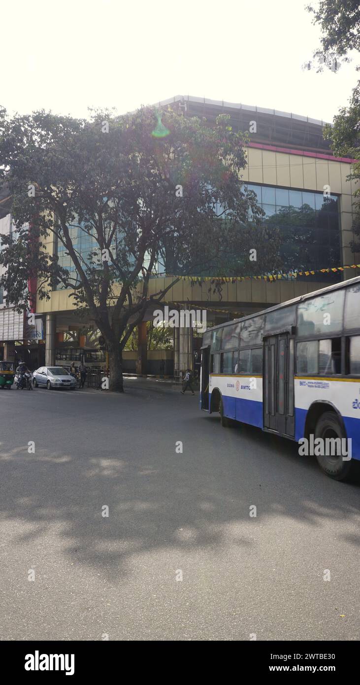 Bangalore, India - January 16 2024: Exterior View of Jayanagar 4th Block BMTC Bus Station building with buses and people. Stock Photo