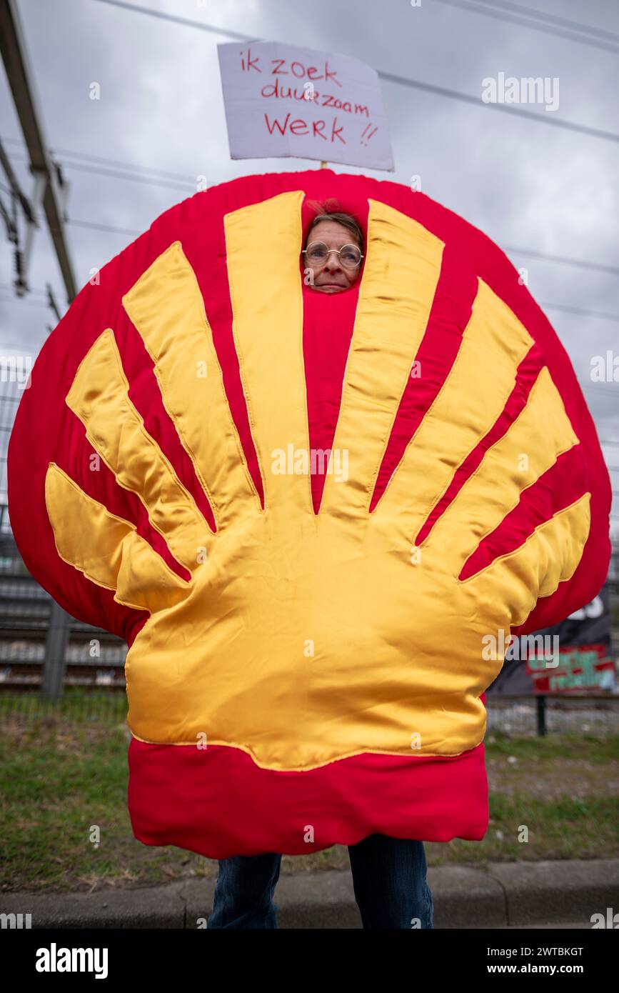 Rotterdam, South Holland, Netherlands. 16th Mar, 2024. An Extinction Rebellion activist, dressed as the Shell logo, holds a sign reading 'Ik Zoek Duurzaam Werk!!' (I'm searching for suitable work!!). Along with protests in Scotland, Germany, Denmark, Norway, and Sweden, Extinction Rebellion Netherlands activists protested at Shell's offices and refinery factories. The aim of these international protestor is to stop drilling in the North Sea. (Credit Image: © James Petermeier/ZUMA Press Wire) EDITORIAL USAGE ONLY! Not for Commercial USAGE! Stock Photo