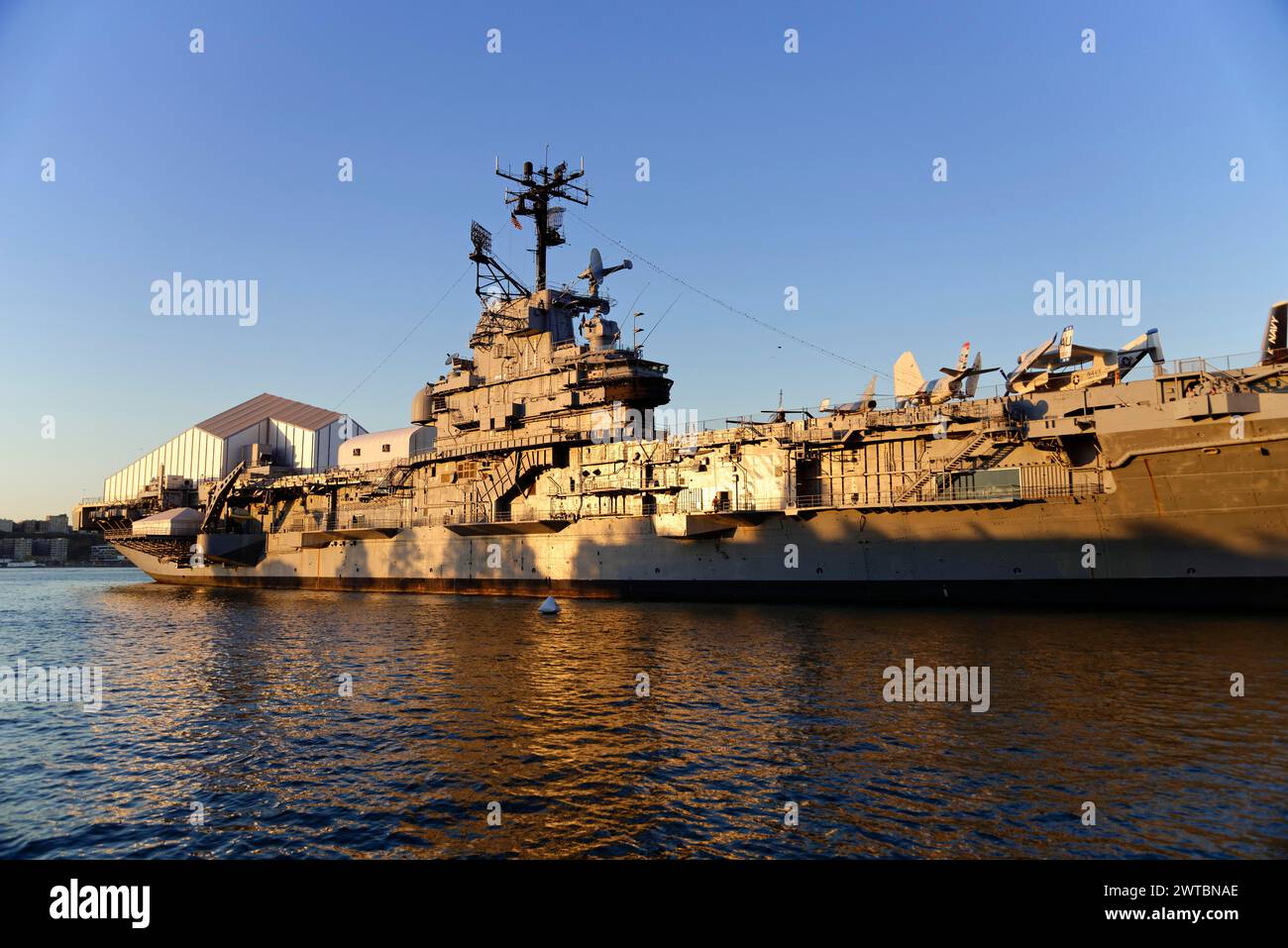 A former warship, now a museum, moored at a harbour in the evening light, on the East River, Manhattan, Brooklyn, New York City, New York, USA, North Stock Photo