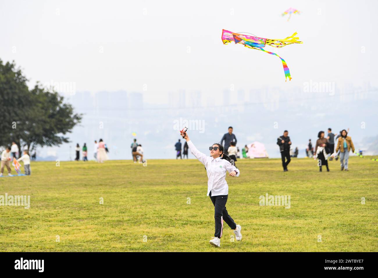 (240317) -- CHONGQING, March 17, 2024 (Xinhua) -- A child flies a kite at Guangyang Isle in southwest China's Chongqing, March 16, 2024. Guangyang Isle, the most extensive green island in the upper reaches of the Yangtze River, has been turned into an ecological restoration and protection 'classroom' for ecotourists and school children.The local ecosystem and biodiversity were once seriously threatened due to real-estate projects in the area. However, the local government brought harmful projects of this sort to a halt in 2017, starting the restoration of the environment on the island. (Xinhua Stock Photo
