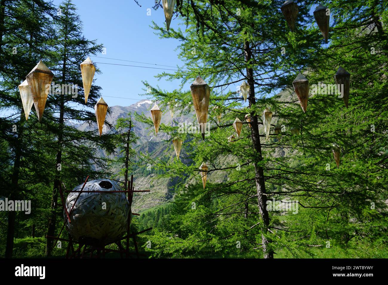 lanterns hanging from larch trees by a wooden giant ball room for resting in the alps, france Stock Photo