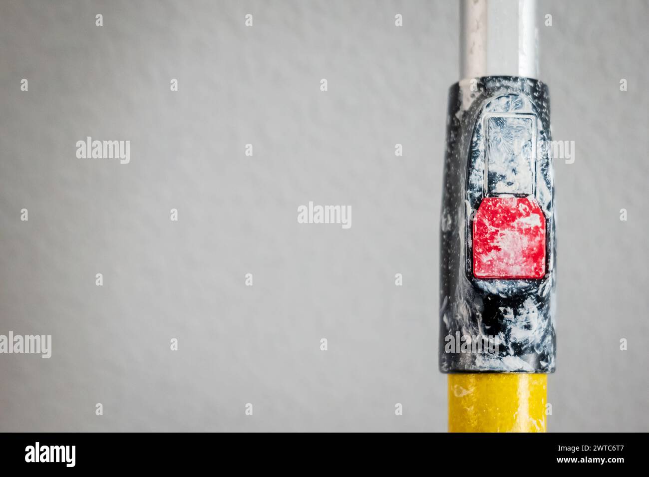 Paint roller extendable pole over painted woodchip wallpaper wall