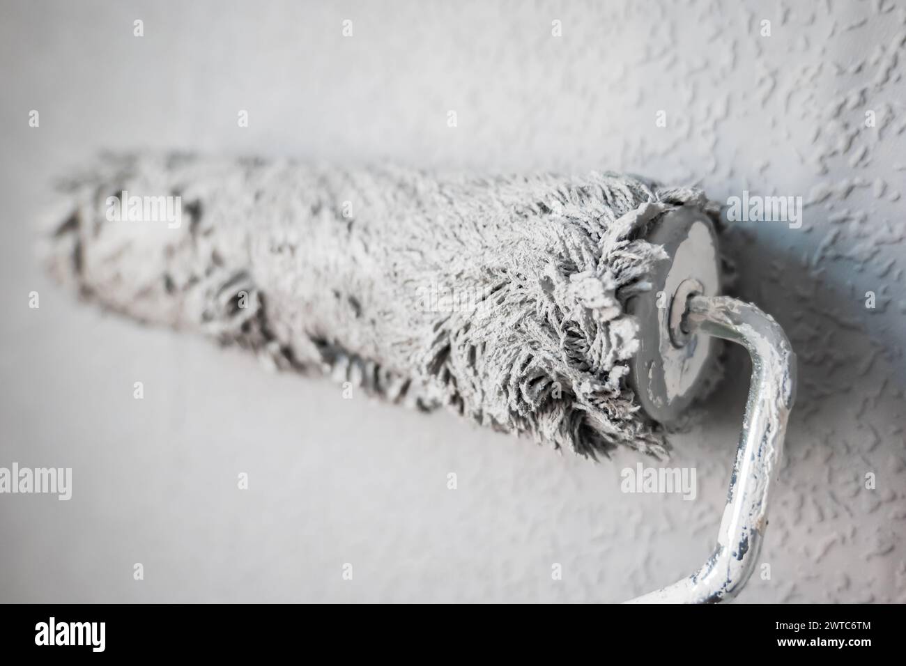 Paint roller extendable pole over painted woodchip wallpaper wall