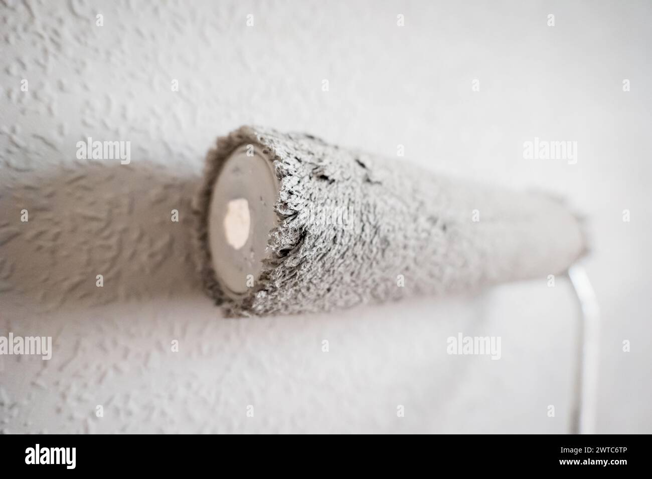 Paint roller extendable pole over painted woodchip wallpaper wall