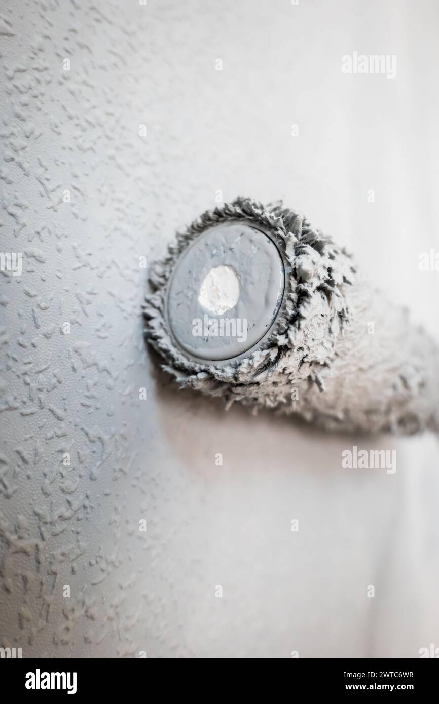 Paint roller extendable pole over painted woodchip wallpaper wall