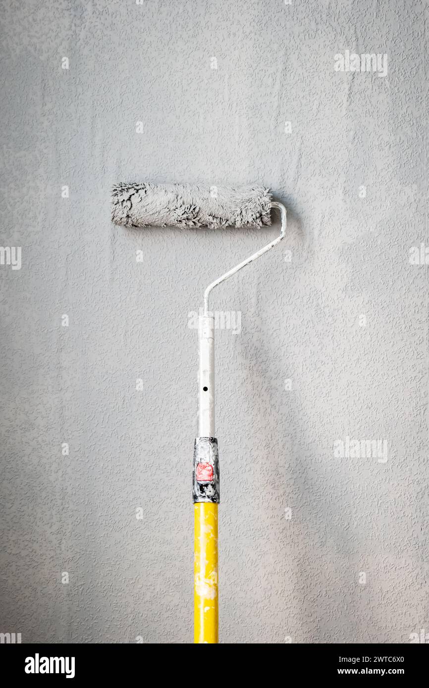 Paint roller extendable pole over painted woodchip wallpaper wall