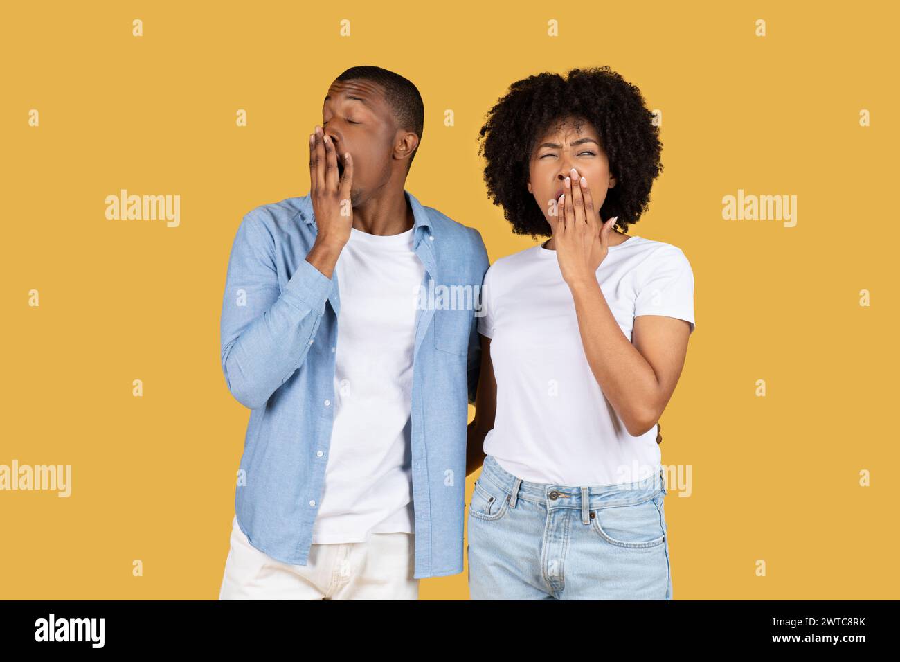 A young couple in casual clothes looking tired and bored, yawning with hands over their mouths Stock Photo