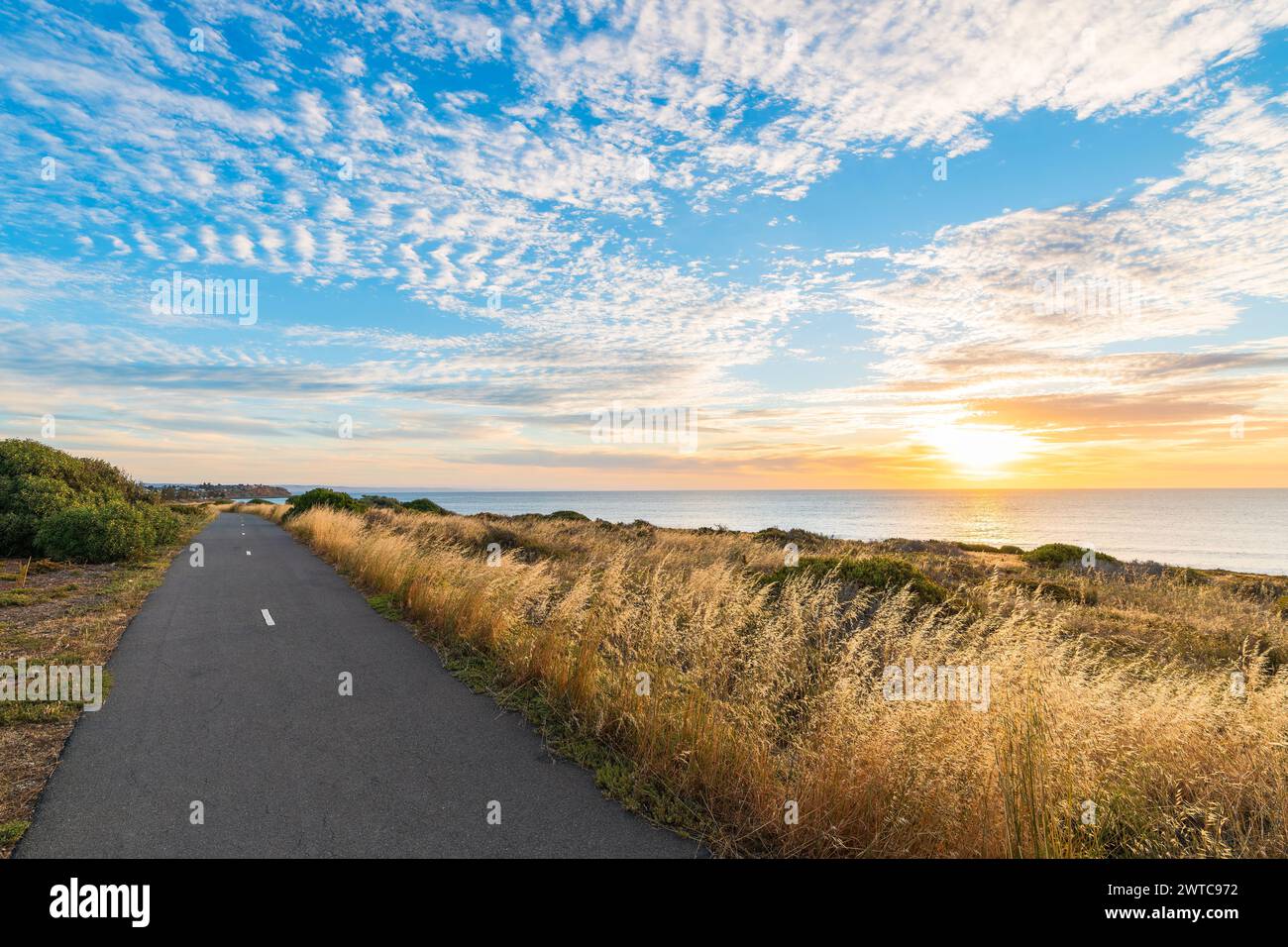 O'Sullivan Beach bicycle track along the shoreline with clouds over the sea during sunset, South Australia Stock Photo