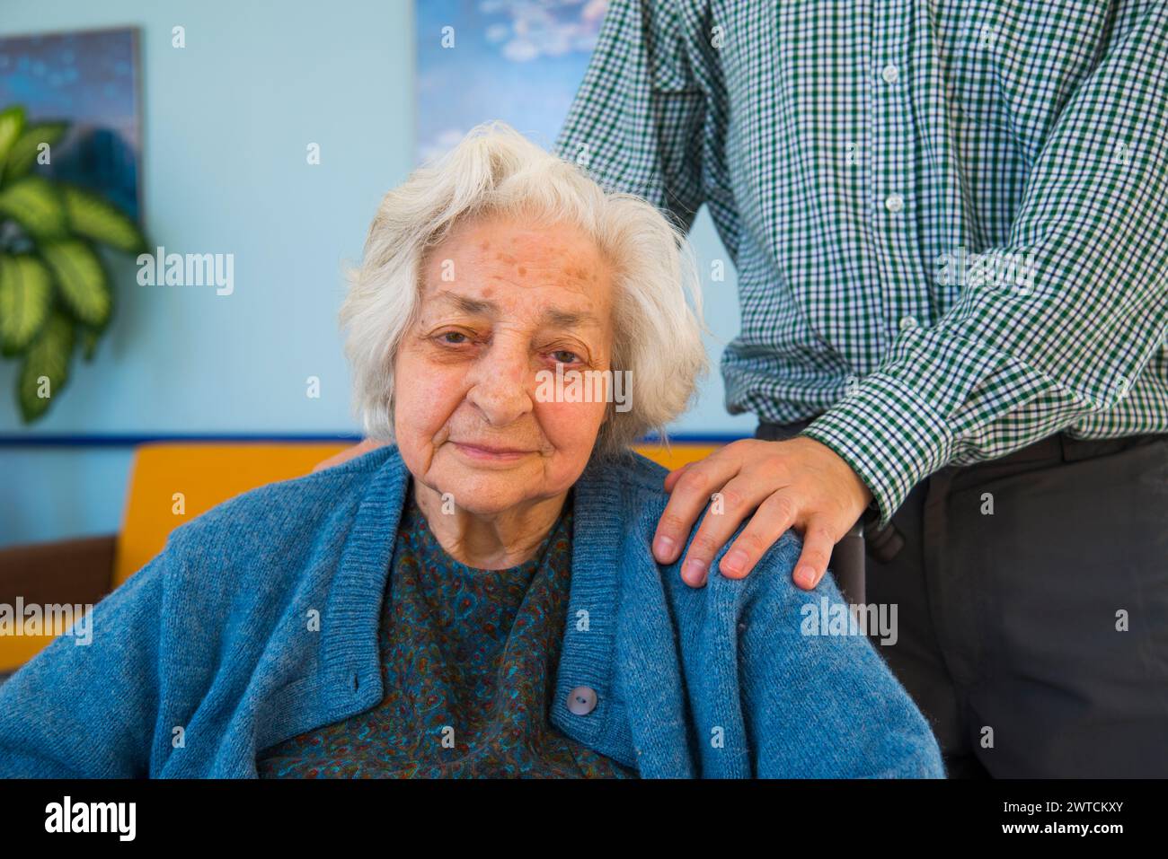 Portrait of old woman in a nursing home and a man putting his hand on her shoulder. Stock Photo