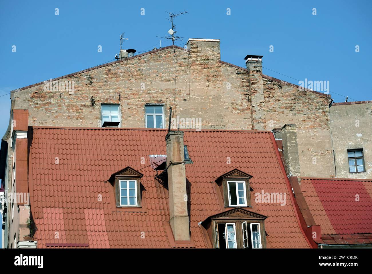Building wall in bad condition above red metal roof in old town of Riga front view Stock Photo