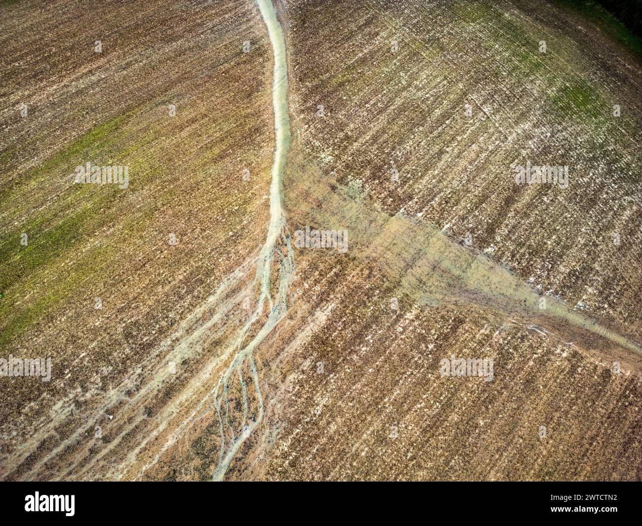 A stream of rain water flows across a ploughed field after torrential ...