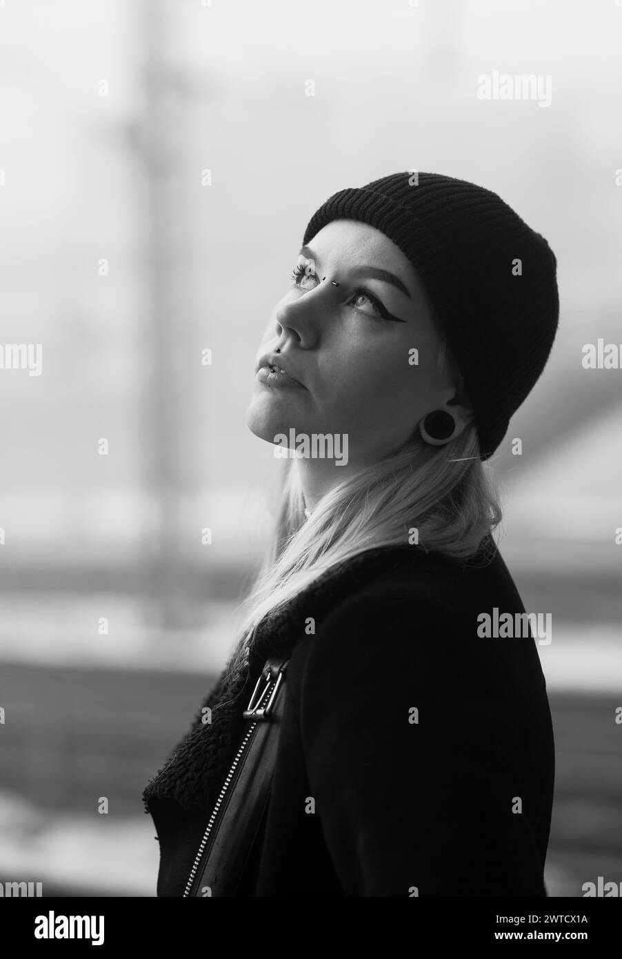 Edgy female model with piercings, beanie and blond hair. Dark tones and blurry background Stock Photo