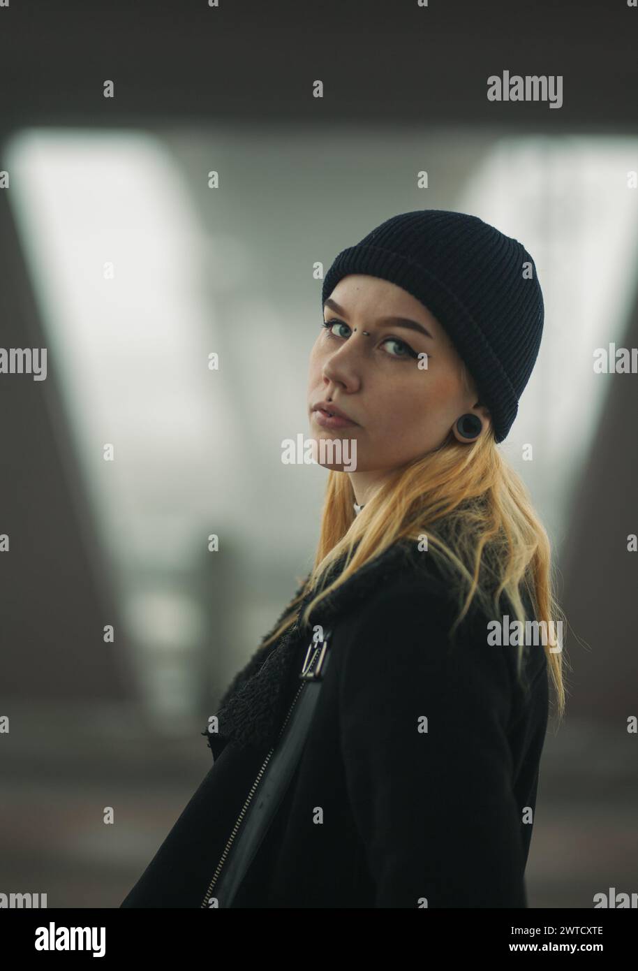 Edgy female model with piercings, beanie and blond hair. Dark tones and blurry background Stock Photo