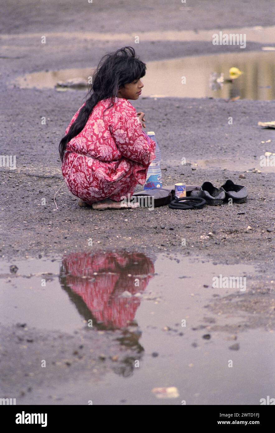 23rd March 1991 An Iraqi girl squats barefoot among the puddles in a ...