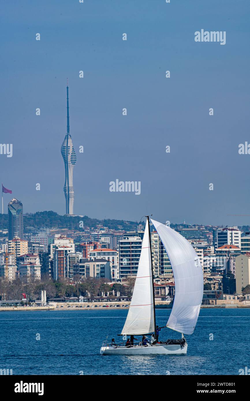 A sailing boat with spinnaker raised, sails past the Camlica,skyscrapers & modern office buildings in Istanbul, Turkey, taken from the Sea of Marmara Stock Photo