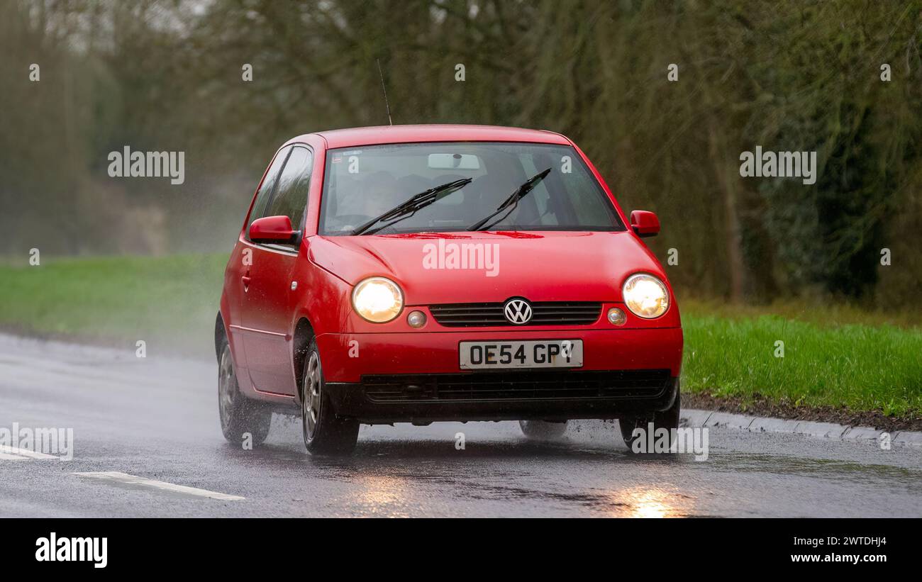 Milton Keynes,UK-Mar 17th 2024: 2004 red Volkswagen Lupo car driving in the rain Stock Photo
