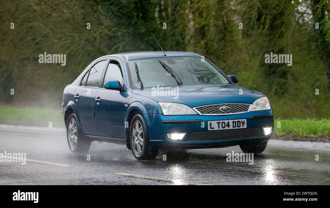 Milton Keynes,UK-Mar 17th 2024: 2006 blue Ford Mondeo ghia diesel engine car driving in the rain Stock Photo