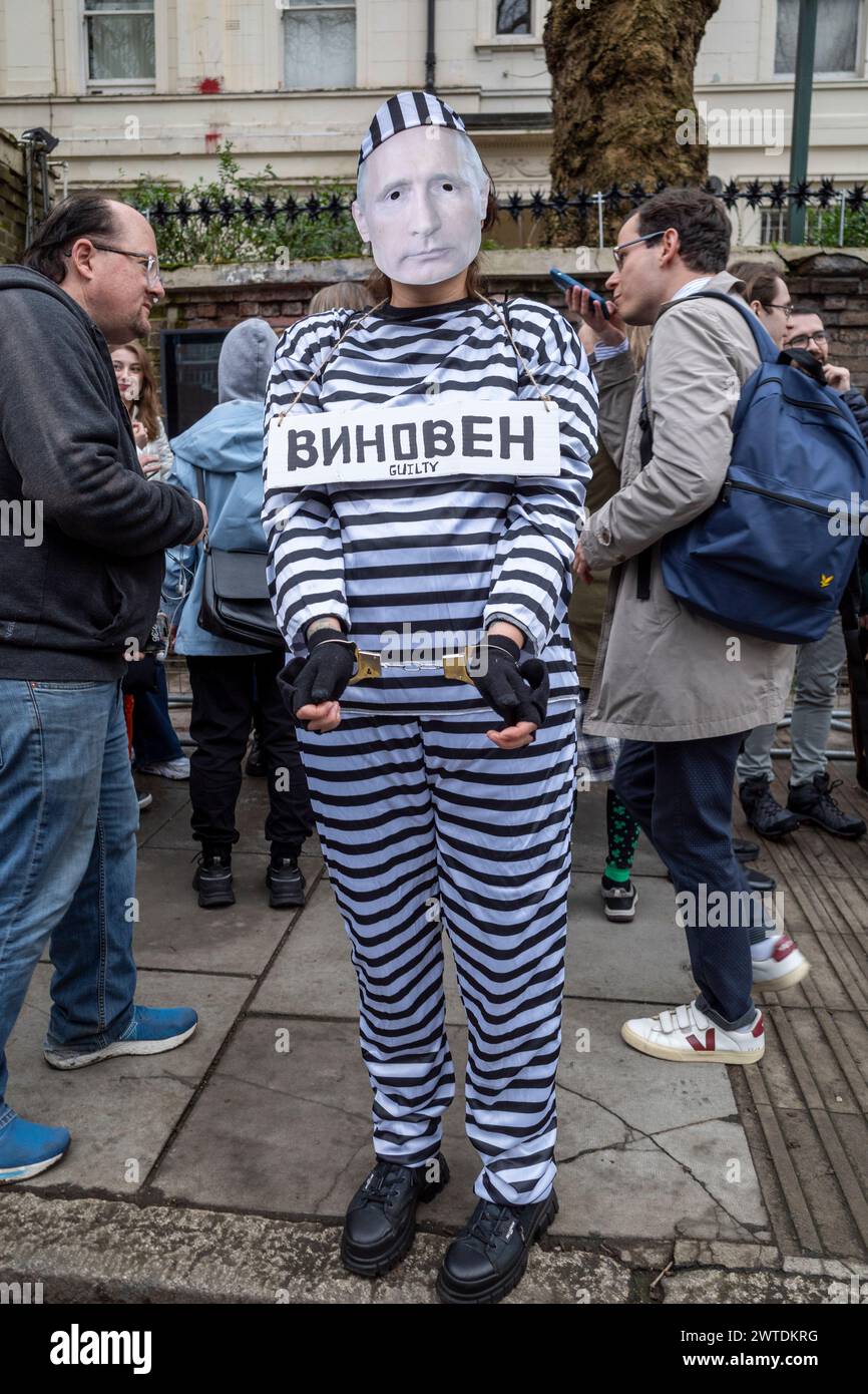 London, UK.  17 March 2024.  A person dressed as a handcuffed Vladimir Putin in a prison suit passes people queuing to vote at the Embassy of Russia near Notting Hill on the final day of voting in the Russian elections.  Yulia Navalnaya, widow of Russian activist Alexei Navalny who died in prison in February, has called for people to attend protests against the regime of Vladimir Putin and overwhelm polling stations as Putin seeks to win an additional term of 6 years.  Many of Putin’s opponents have either been killed, imprisoned or are in exile.  Credit: Stephen Chung / Alamy Live News Stock Photo