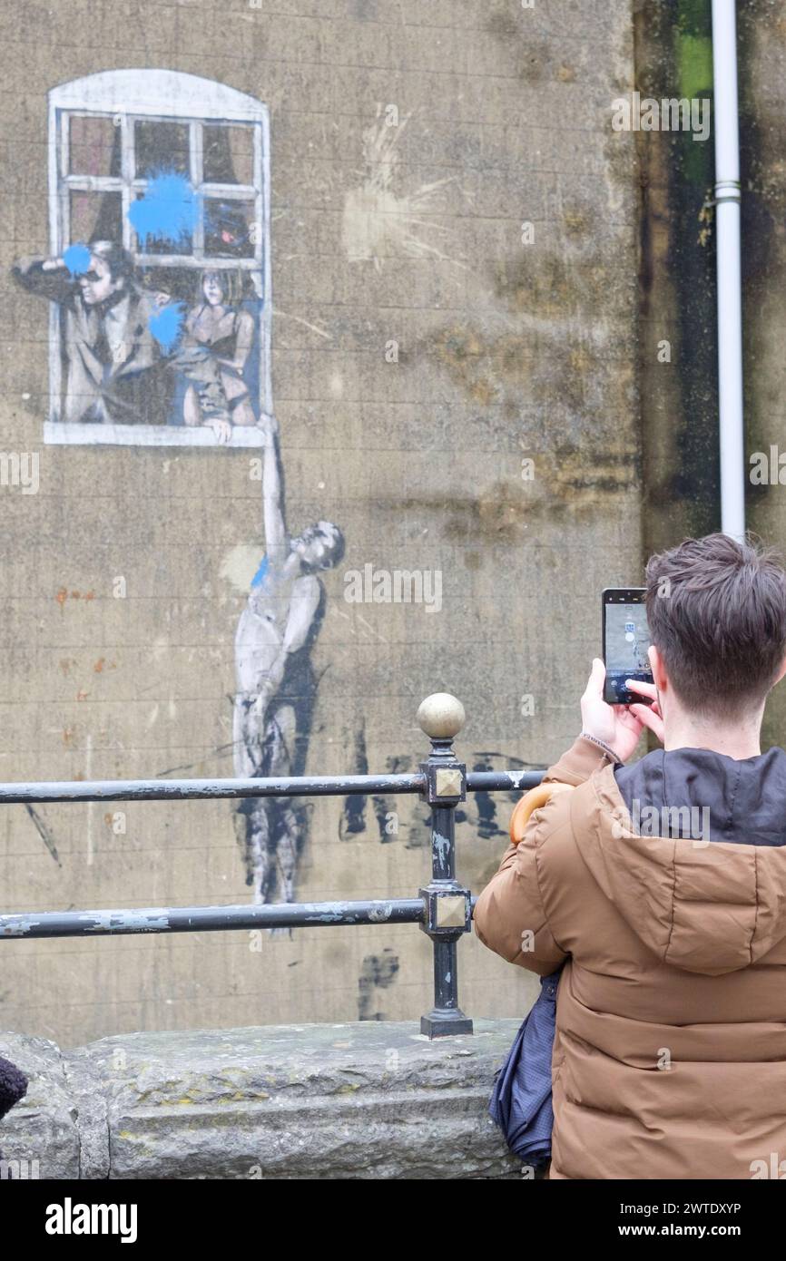 Young man taking a phone picture of Banksys picture Well Hung Lover on Park st Bristol Stock Photo