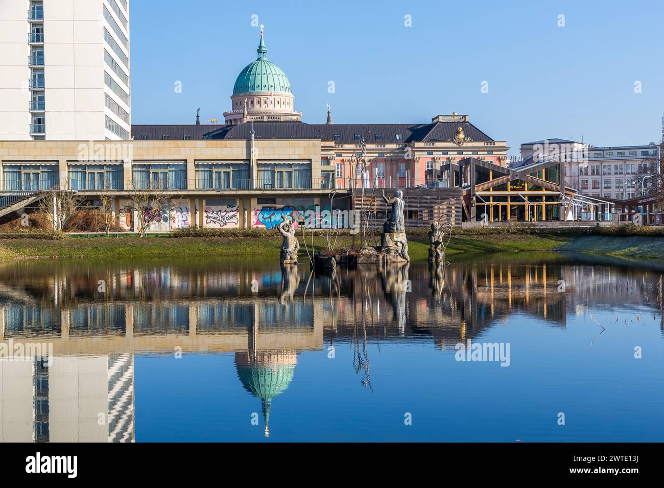 City view of Potsdam with the façade of the former city palace, the simple brutalist architecture of the Mercure Hotel and the Neptune Basin with steel fog light sculpture 'Neptune's Triumph'. Lustgarten, Potsdam, Brandenburg, Brandenburg, Germany Stock Photo
