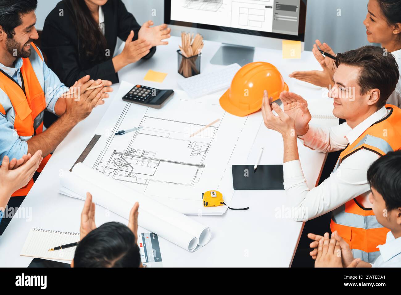 Diverse group of civil engineer and client feels excited and applauding after successful agreement on architectural project, review construction plan Stock Photo