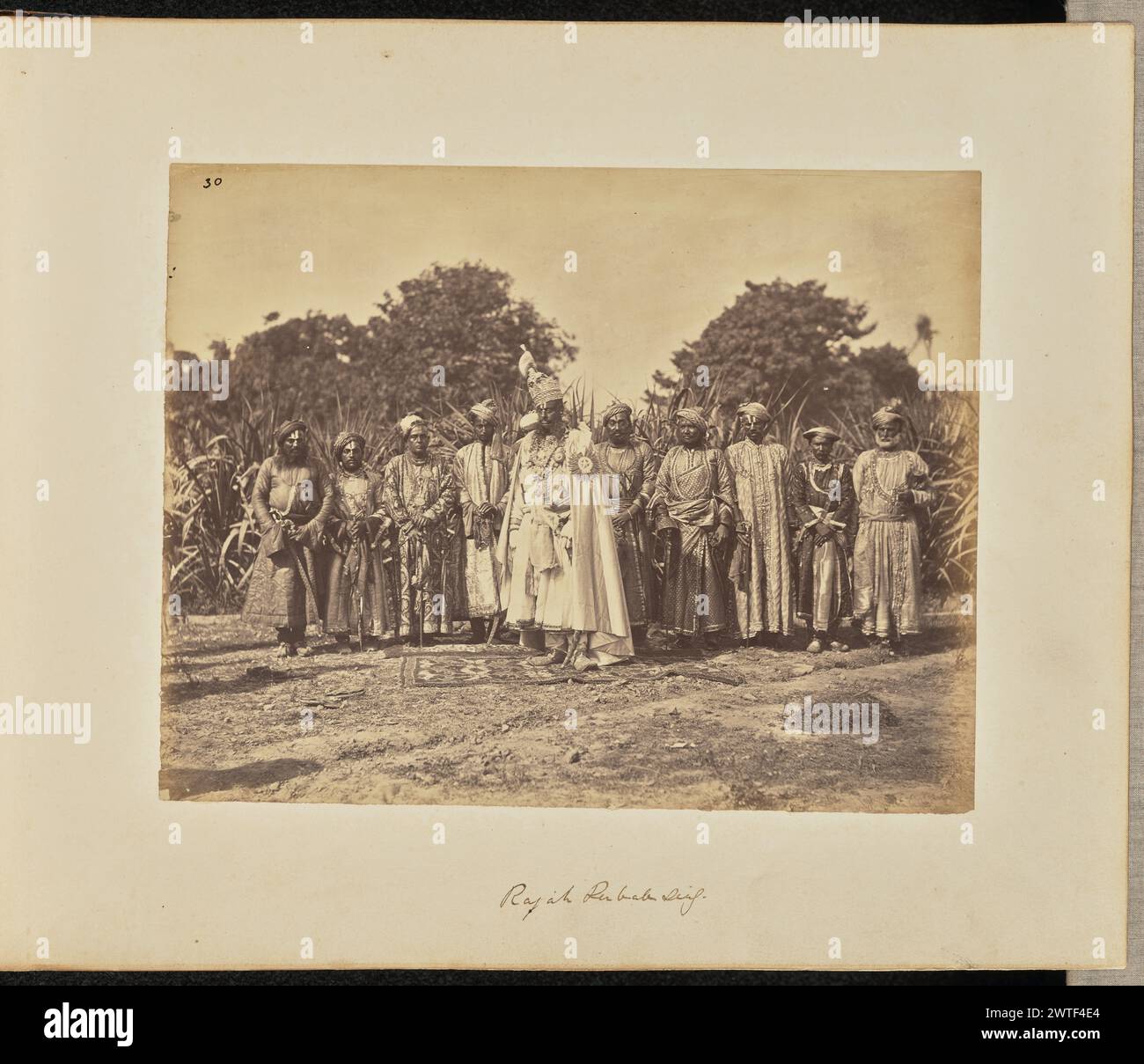 Rajah Rubab Sing. Unknown, photographer about 1866–1870 Group portrait of a ruler of an Indian princely state, possibly Maharaja Raghuraj Singh, the Maharaja of Rewa, and his retinue in an outdoor setting. The Maharaja wears a glittering crown and the mantle of the Order of the Star of India. (Recto, print) upper left, in black ink: '30'; (Recto, mount) lower center, in brown ink: 'Rajah Rubab Sing.'; (Verso, mount) lower left, in pencil: 'A48.76'; Stock Photo