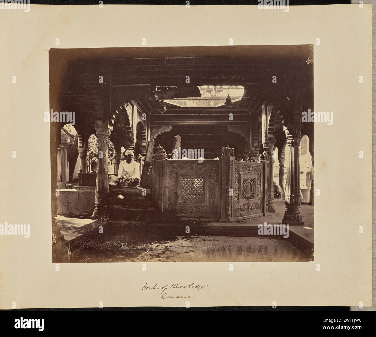 Well of Knowledge. Benares. John Edward Saché, photographer (Prussian or British, born Prussia, 1824 - 1882) about 1868 A man sits next to the well in Gyanvapi Mosque, also known as the Well of Knowledge. An intricately carved screen is installed around the well. (Recto, print) lower right, inscribed in the negative: '324'; (Recto, mount) lower center, in brown ink: 'Well of Knowledge. / Benares.'; (Verso, mount) lower left, in pencil: 'A48.48 (Saché)'; Stock Photo