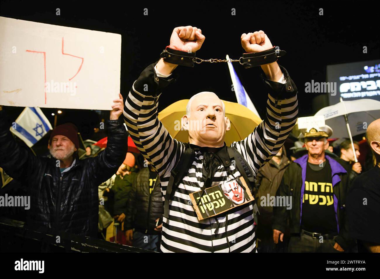 Tel Aviv, Israel. 23rd Dec, 2023. A protestor dressed in a convict uniform and a Benjamin Netanyahu mask is seen next to a placard that reads Ã¬Go away!Ã® during a demonstration. Thousands of Israelis protest in the pouring rain calling for Prime Minister Benjamin Netanyahu's ousting. (Credit Image: © Matan Golan/SOPA Images via ZUMA Press Wire) EDITORIAL USAGE ONLY! Not for Commercial USAGE! Stock Photo