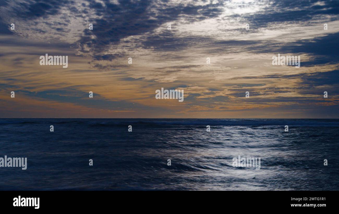 Sunset cloudy sky over the coast line. Stock Photo