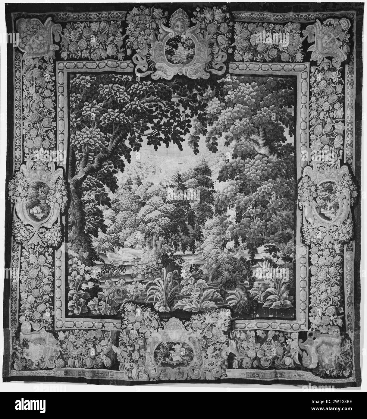 Landscape. unknown c. 1640-1670 Tapestry Dimensions: H 11'9' x W 11'4' Tapestry Materials/Techniques: unknown Culture: French Weaving Center: Aubusson Ownership History: French & Co. Lush landscape with flowering plants & trees intersected by narrow river in foreground (BRD) richly decorated border framed by strips of stylized quatrefoil with garland of flowers & leaves interrupted by elaborate reserves: (L & R BRD) landscape cartouche suspended by tied ribbon & topped with female head with bunch of flowers on either side & framed by festoons; (UPR BRD) male mask above landscape cartouche fram Stock Photo