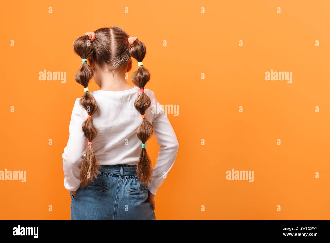 little-girl-with-beautiful-hairstyle-on-orange-background-back-view
