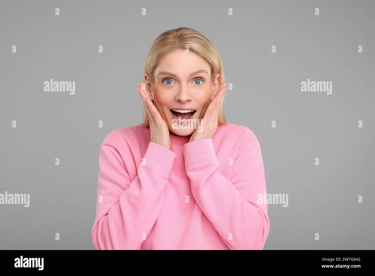 Portrait of happy surprised woman on grey background Stock Photo - Alamy