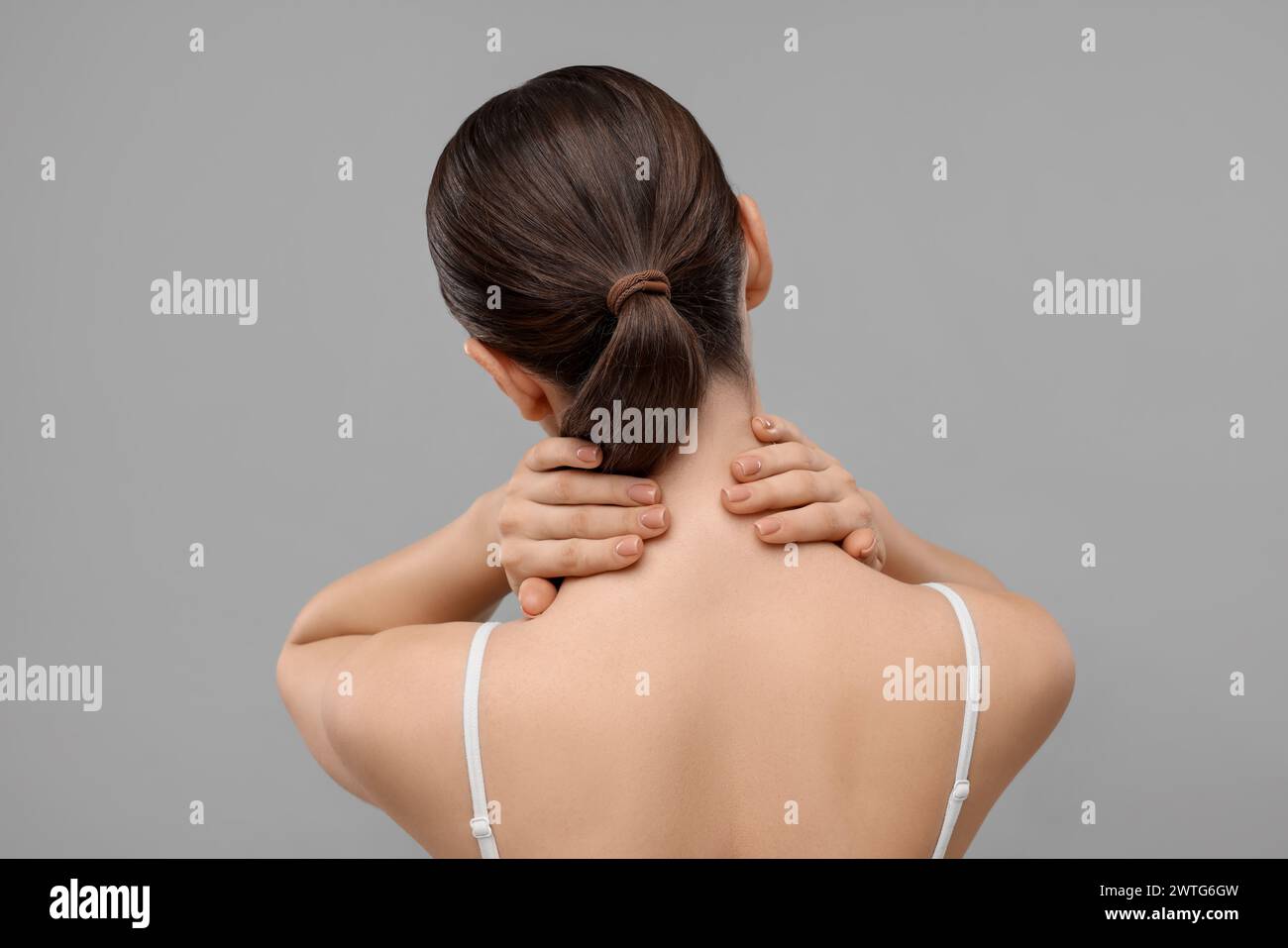 Woman touching her neck on grey background, back view Stock Photo - Alamy