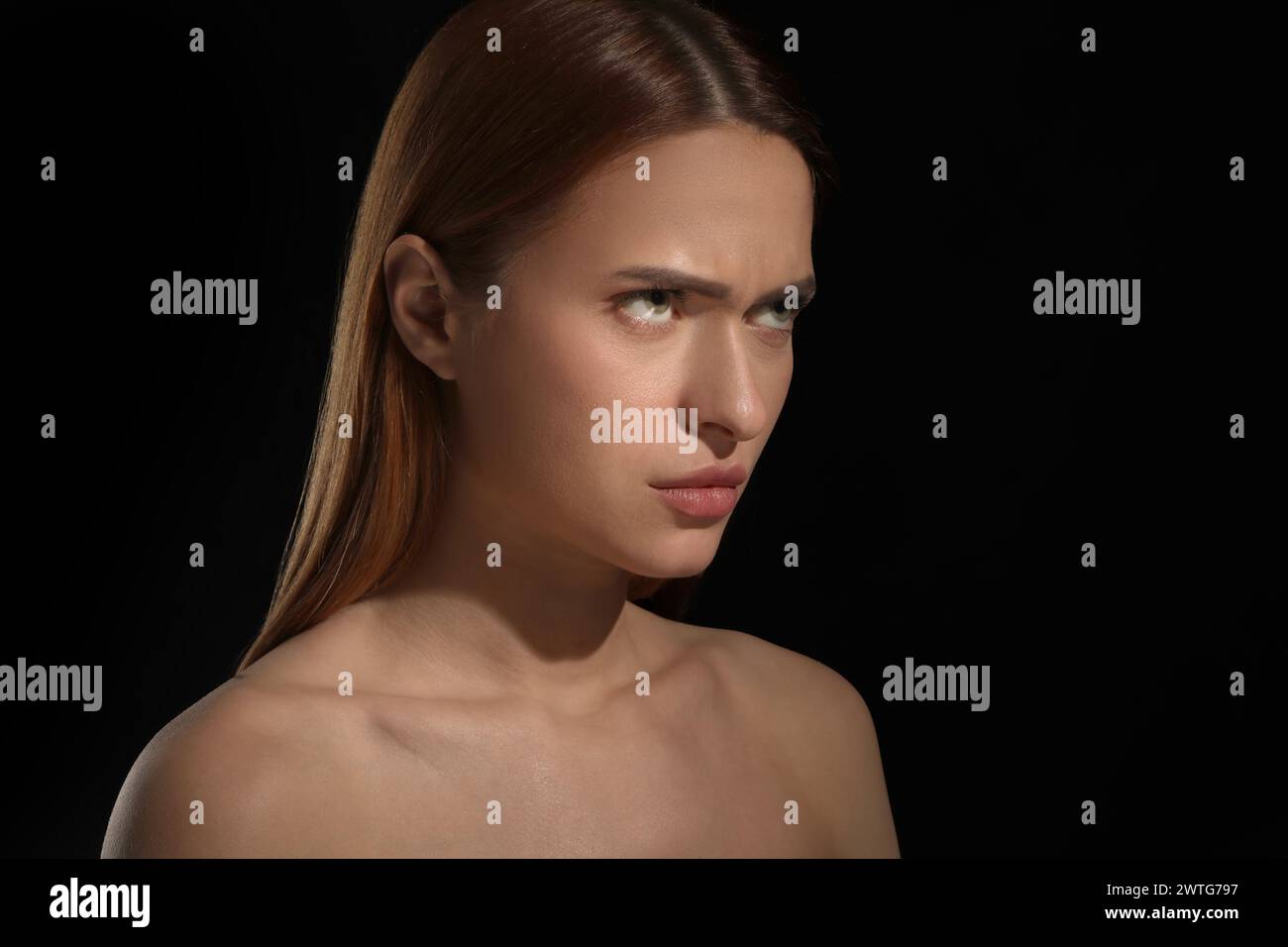 Evil eye. Young woman with scary eyes on black background Stock Photo