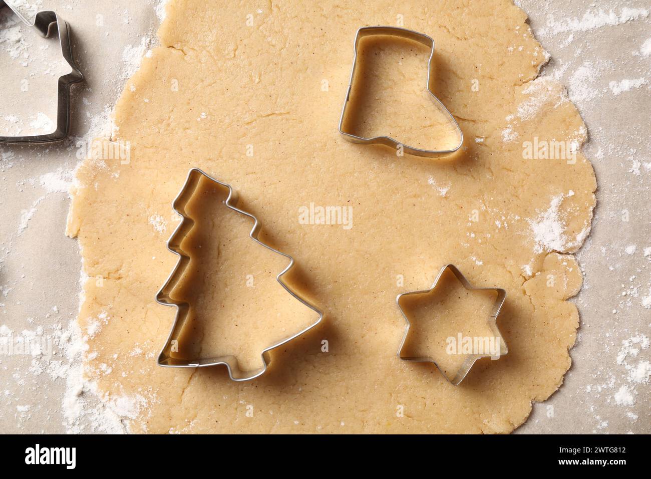 Making Christmas cookies. Raw dough and metal cutters on parchment paper, flat lay Stock Photo