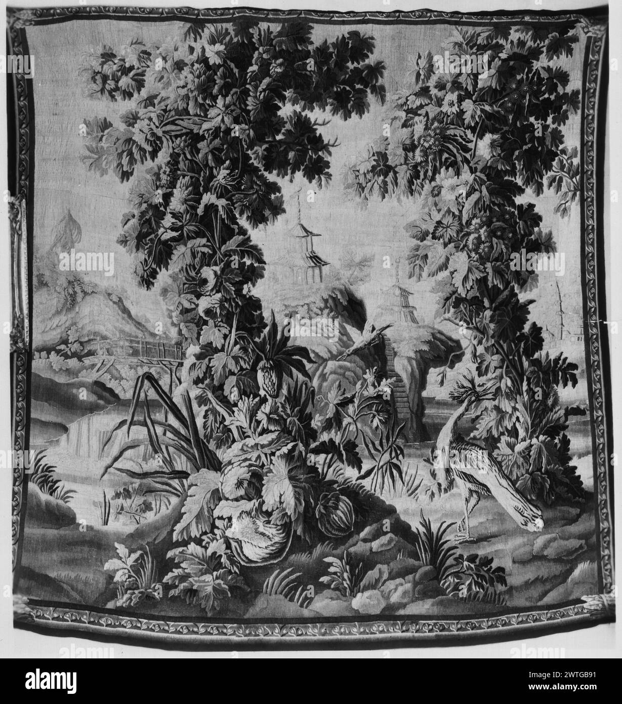 Fantastic landscape with outcrop and wooden bridge. Pillement, Jean (French, 1728-1808) (designed after) [painter] Dorliac, Jacques (French, fl. 1715-1742) (workshop) [weaver] c. 1725 Tapestry Materials/Techniques: unknown Culture: French Weaving Center: Aubusson Ownership History: Countess Guy de Pourtales coll., Paris (?) [written on verso of photo]. French & Co. Landscape with bird in foreground framed by pair of leafy, flowering trees; outcrop with staircase leading to pavilion; hill with larger pavilion in the distance & bridge (L) (BRD) narrow border with stylized trefoil-like band There Stock Photo