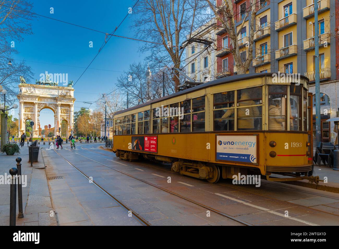 An old fashioned electrified tram facing the Arch of Peace in the centre of Milan close to the main city park. The trams are an ideal way of public tr Stock Photo
